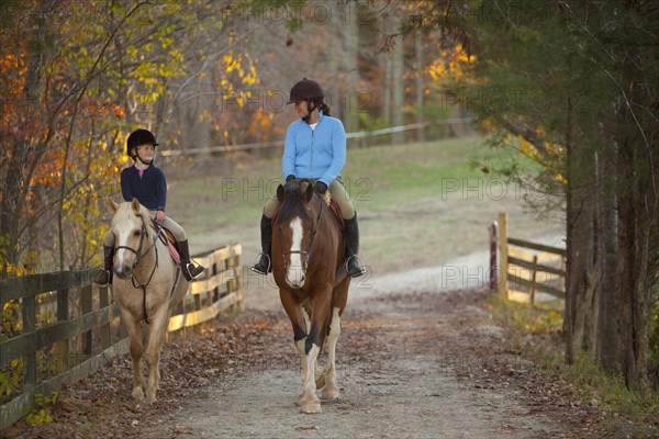 Caucasian girl and trainer riding horses