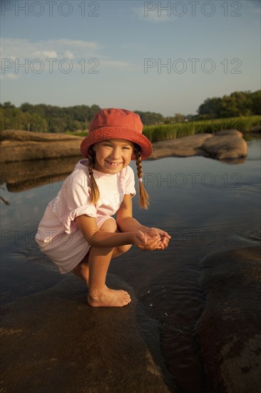 African American girl scooping water from river