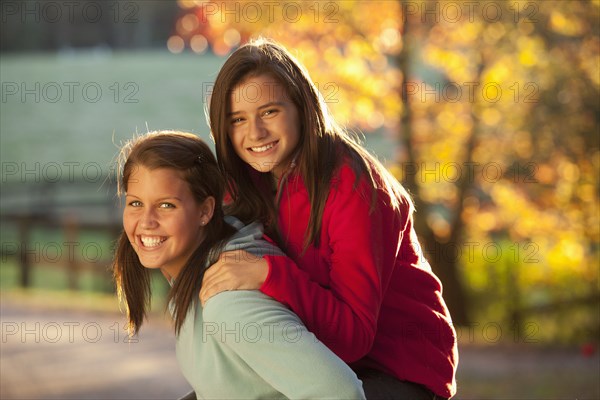 Caucasian girl carrying friend on her back