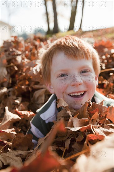 Caucasian boy playing in autumn leaves