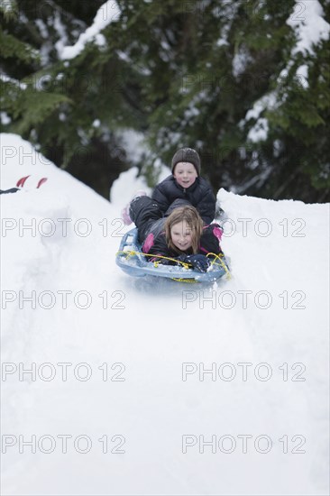Caucasian children sledding in snow