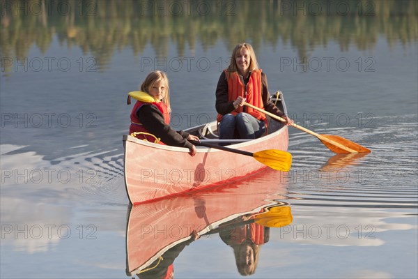 Caucasian mother and daughter canoeing on Lake Edith