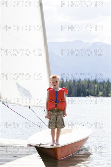 Boy in life jacket standing on sailboat