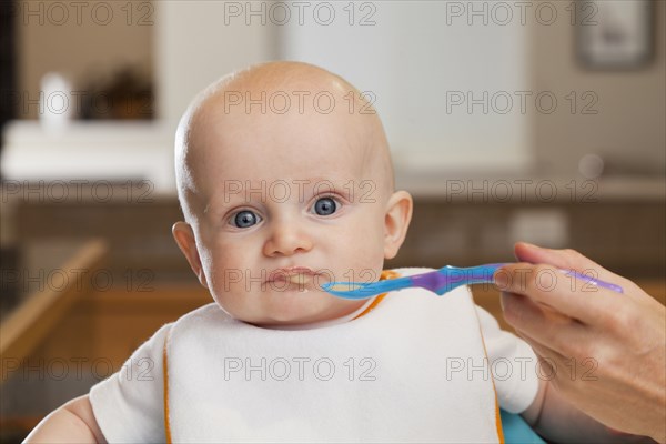 Caucasian mother feeding baby in high chair