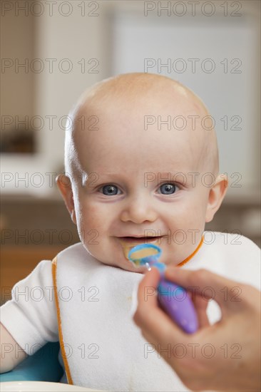 Caucasian mother feeding baby in high chair