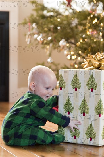 Caucasian baby playing with Christmas present