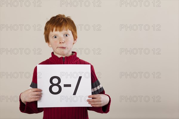 Caucasian boy holding card with awkward face