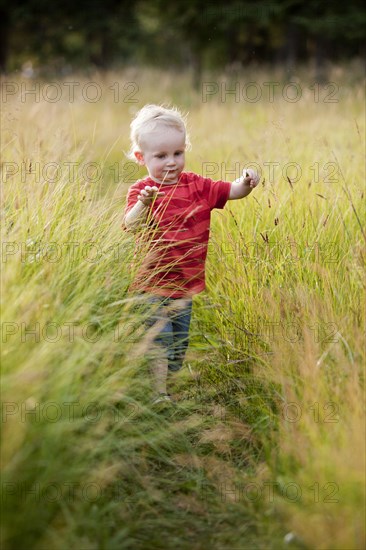Caucasian boy playing in tall grass