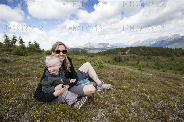 Caucasian mother and son sitting on remote hilltop