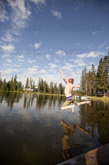 Caucasian boy jumping into lake