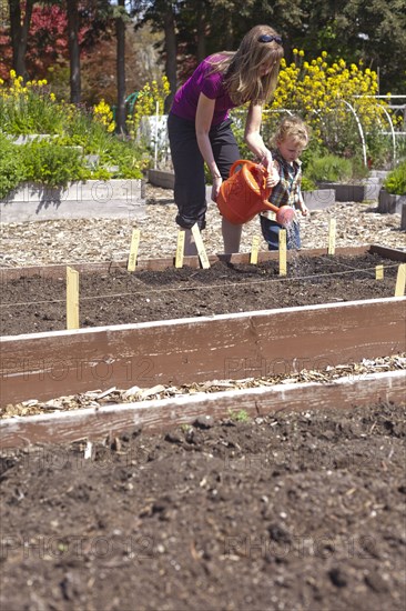 Caucasian mother and son watering plants in garden