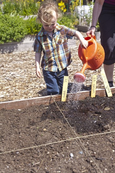 Caucasian mother and son watering plants in garden