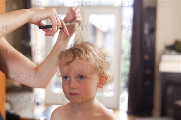 Caucasian mother cutting hair of son