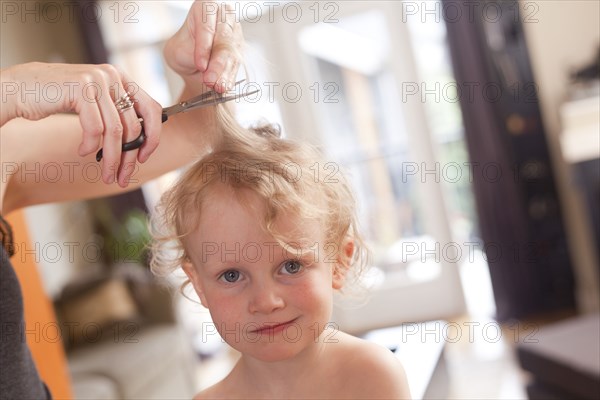 Caucasian mother cutting hair of son