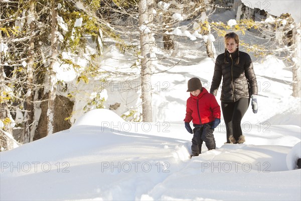 Caucasian mother and son snowshoeing on path