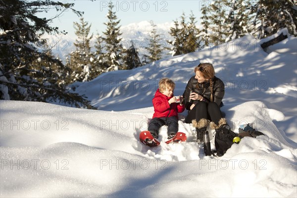 Caucasian mother and son drinking hot cocoa in snow