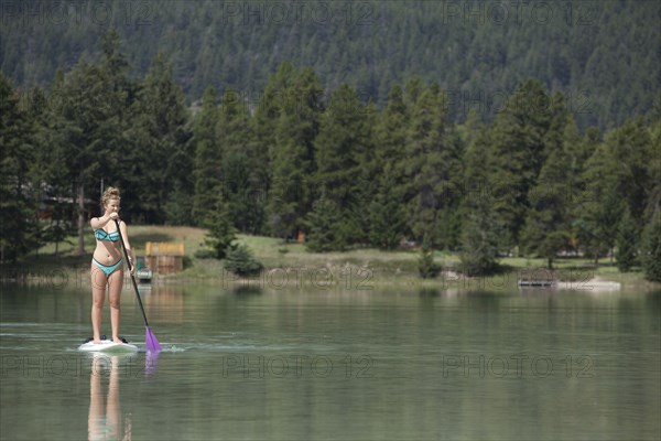 Caucasian girl paddleboarding on lake