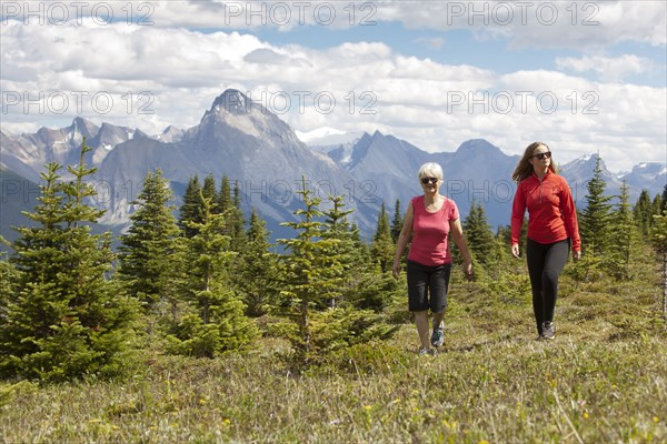 Caucasian girl and grandmother walking in woods near mountain