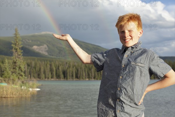 Caucasian boy posing at lake catching rainbow