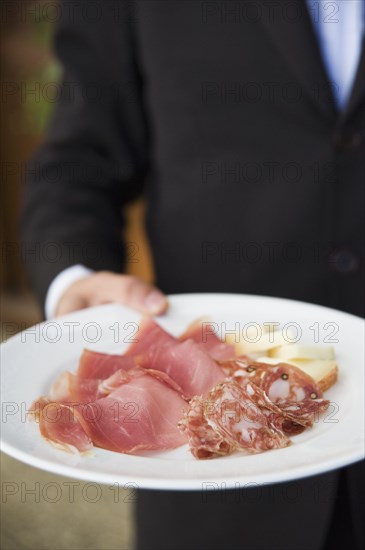 Waiter carrying plate of cured Italian meats