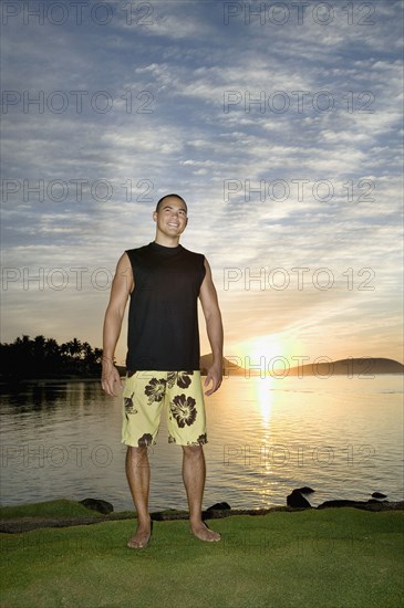 Asian man next to water at sunset