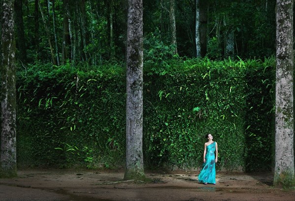 Hispanic woman wearing evening gown in woods