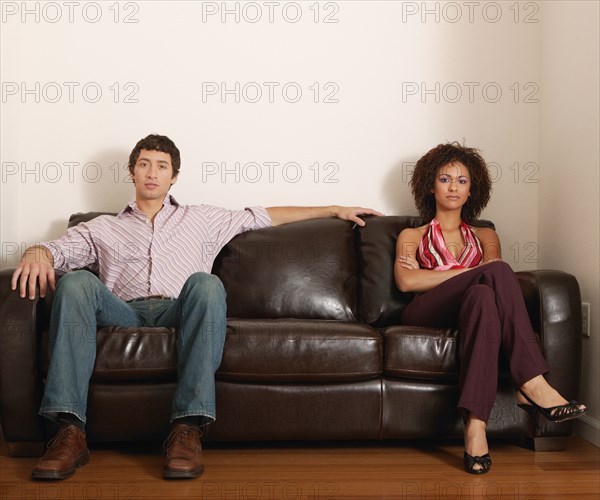 Multi-ethnic couple sitting on sofa