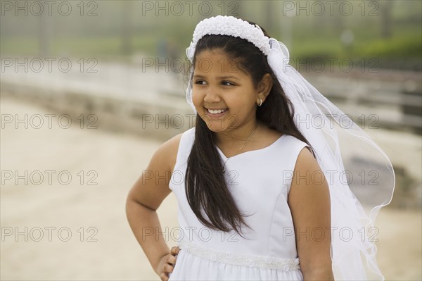 Hispanic girl wearing first communion gown and veil