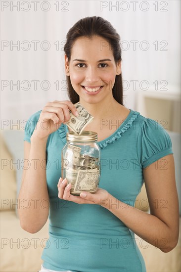 Hispanic woman putting money in jar