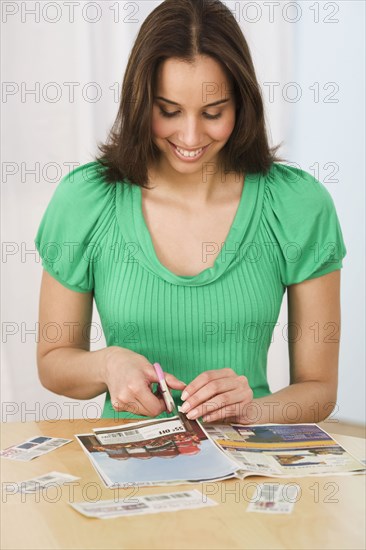 Hispanic woman clipping coupons