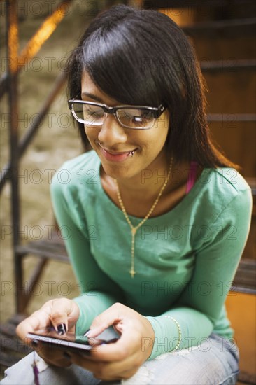 Hispanic girl text messaging on staircase