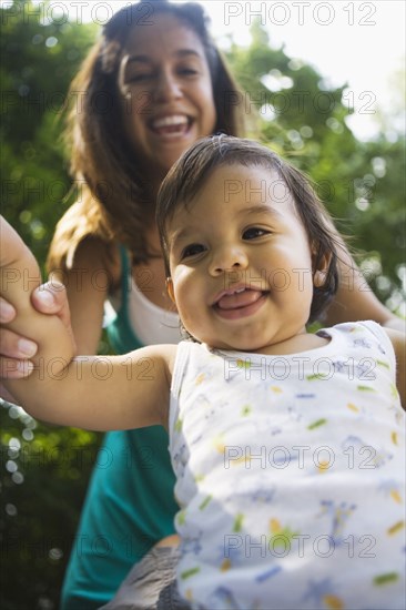 Hispanic mother helping baby boy to walk