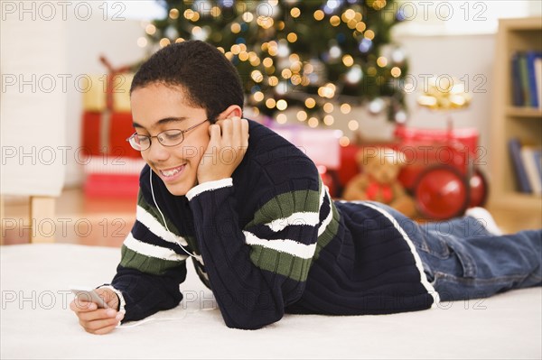 Hispanic boy listening to mp3 player at Christmas