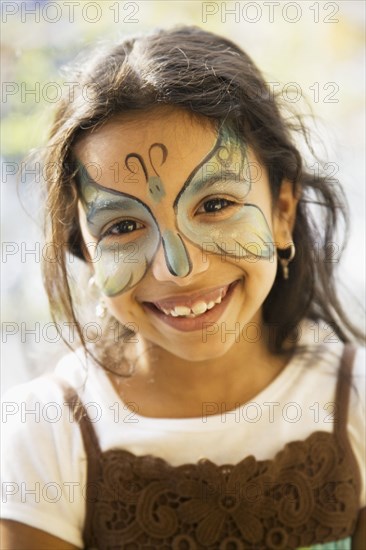 Close up of Hispanic girl with butterfly painted on face