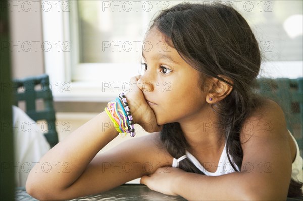 Pensive Hispanic girl with head in hands