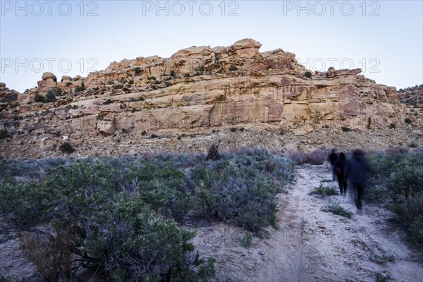 People walking on trail to rock formation