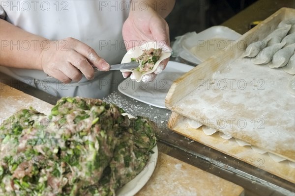 Chef spreading filling in dumpling