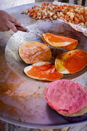 Hand flipping fresh tortillas in pan