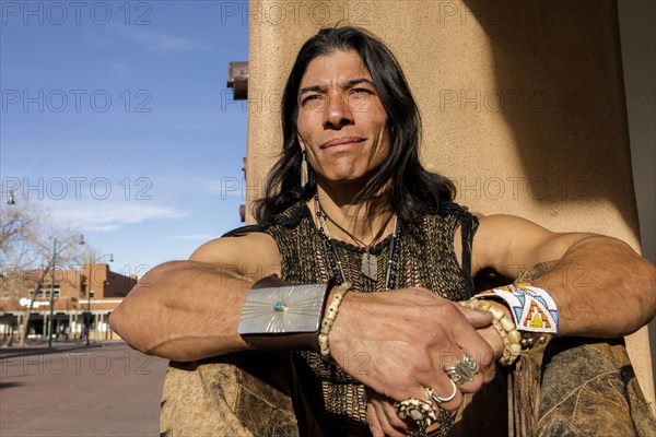 Native American man sitting against post