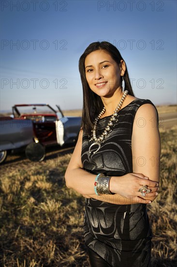 Portrait of smiling woman standing in grass near car