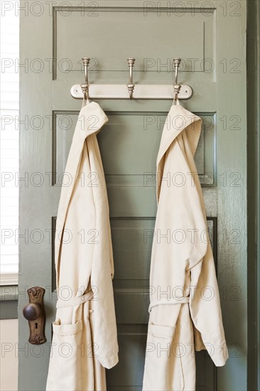 Bathrobes hanging on hooks on door