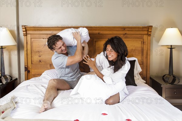 Playful couple having pillow fight on bed