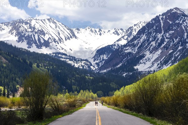 Distant people bicycling on road to mountain