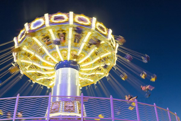Illuminated spinning amusement park ride at night