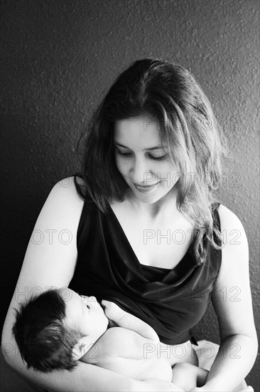 Mother holding baby son near wall