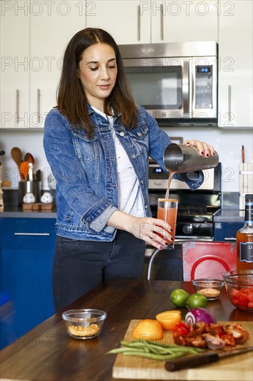 Woman pouring cocktail in kitchen