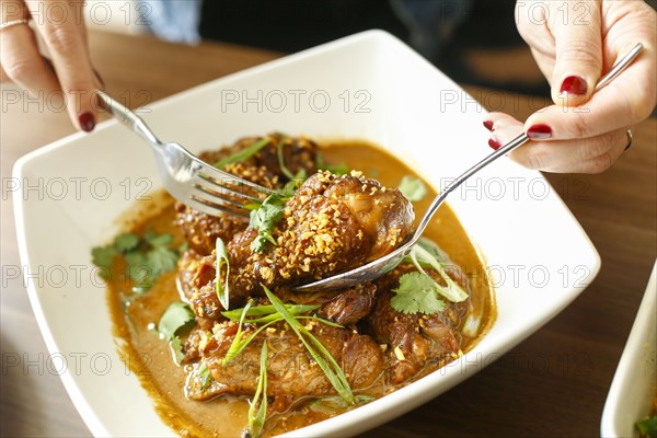 Woman holding meet in bowl with fork and spoon