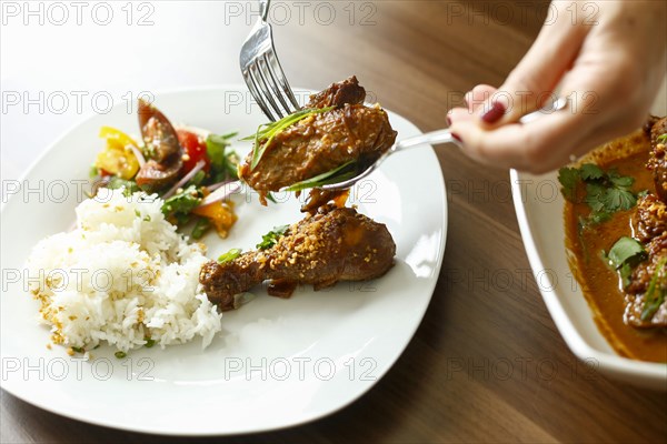 Woman holding meat over plate with fork and spoon