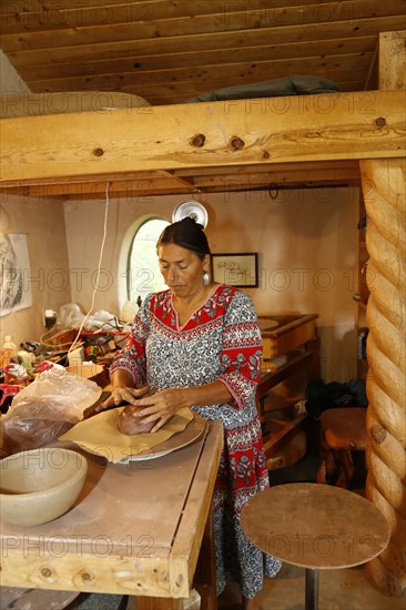 Mixed race woman shaping clay in art studio