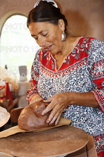 Mixed race woman shaping clay in art studio